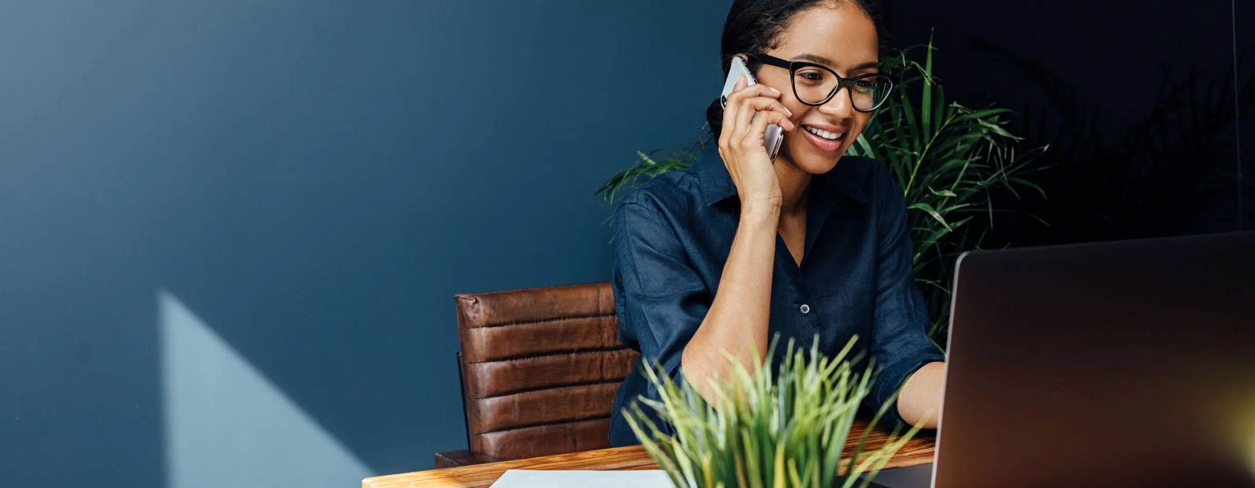 A woman is on the phone and looking towards her computer screen. She's smiling. It appears that she is on the phone with a nonprofit she recently donated to.