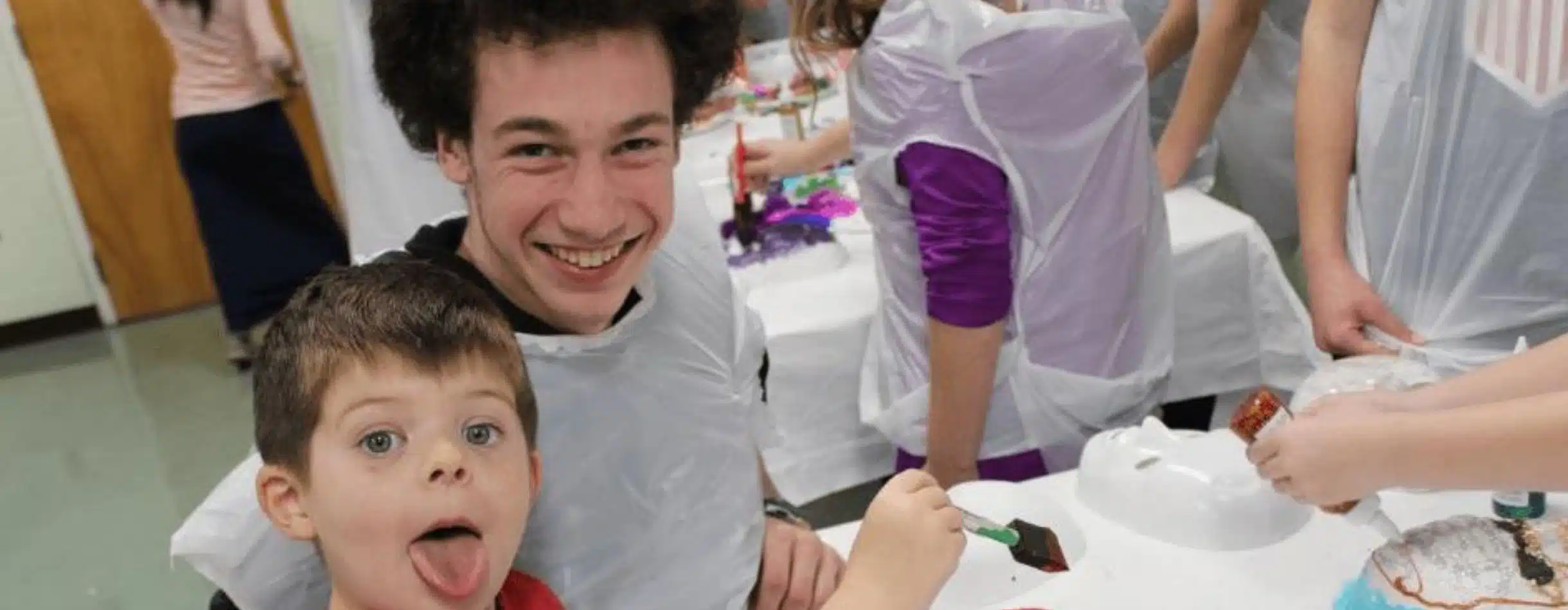 Two young men from Chabad of Charlotte smile for the camera as they paint on canvas as part of a event the nonprofit set up.