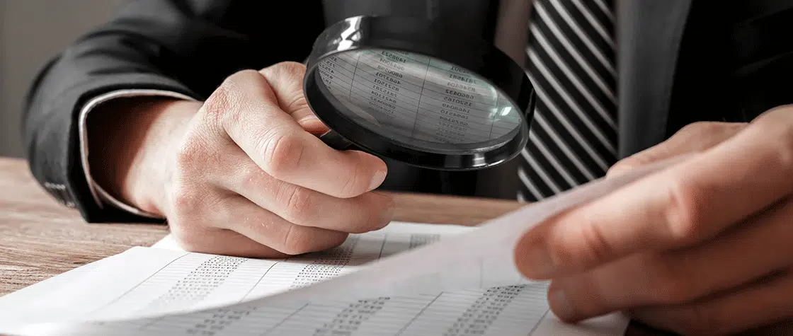 man studying document with magnifying glass